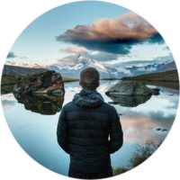 Man stanidng over a lake looking at the clouds